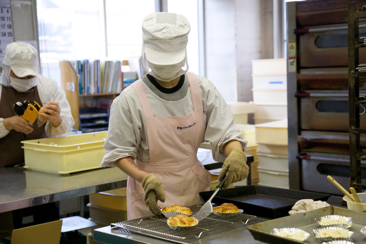 焼きあがったパンを取り出す利用者さん