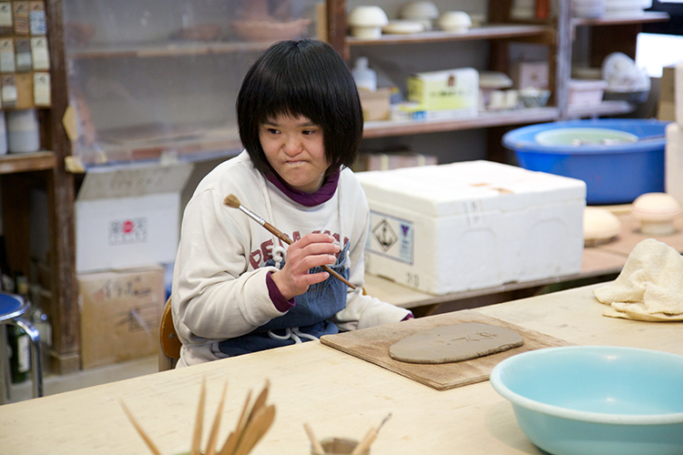 陶芸に絵入れをする利用者さん写真