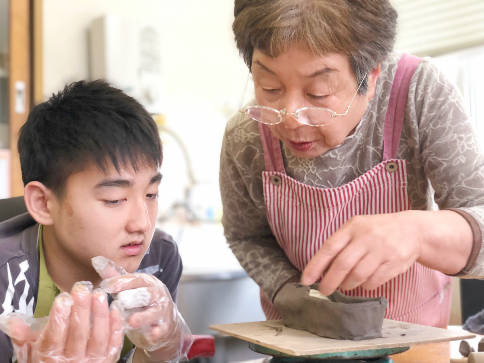 陶芸をする利用者さんと指導するスタッフの写真