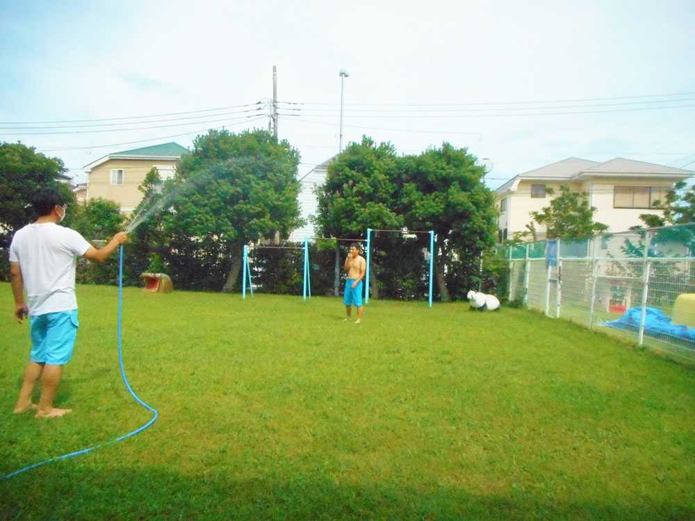 園庭でホースの水をまいて水浴び